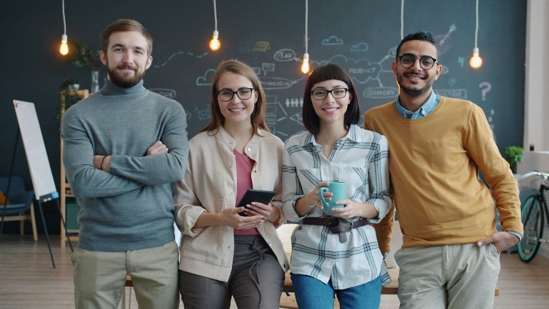 Four diverse colleagues standing together in an office.